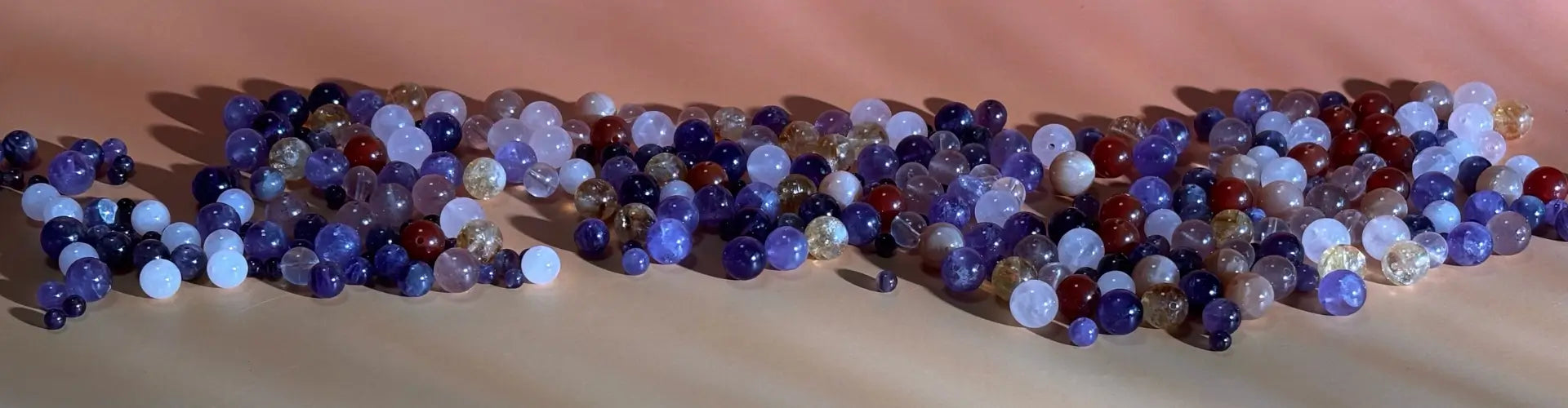 Colourful natural gemstonebeads scattered on a beige surface