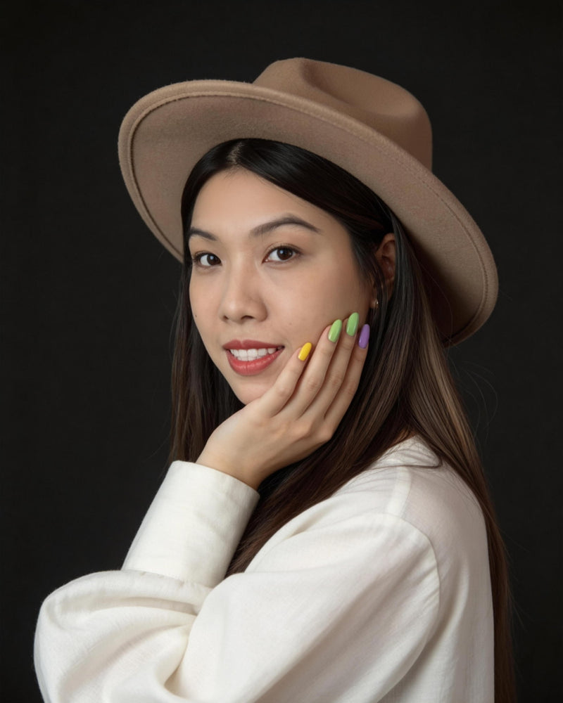 Founder of House of Iris  wearing a beige hat and white blouse with colourful nail polish against a black background