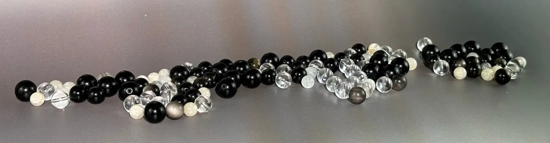 Set of black, white, and clear quartz beads on a grey surface