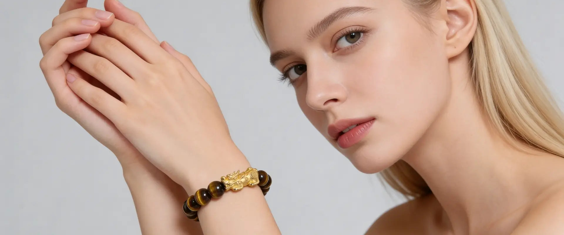Woman wearing a Tiger eye PiXiu bracelet on a plain background
