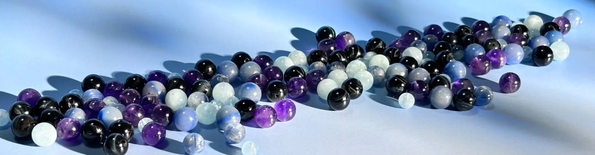Colourful water element beads in black, white, and purple on a light blue background